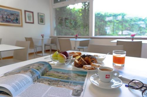 una mesa con un libro y un plato de comida y una taza de café en Hotel Mistral en Oristano