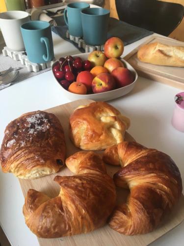 a table with croissants and apples and a plate of bread at Le4bergheim Chambre d'hôtes in Bergheim