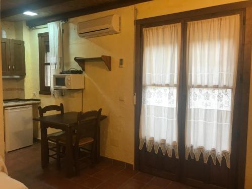 a kitchen with a table and a door with a window at Casa Rural Cortijo La Ajedrea in Siles
