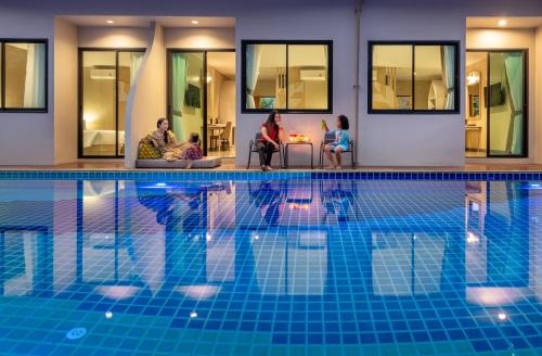 un grupo de personas sentadas alrededor de una piscina en At Rice Resort en Nakhon Nayok