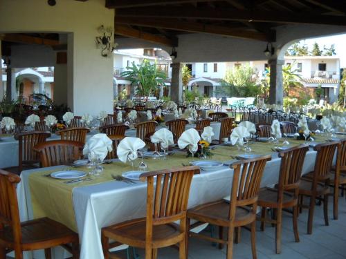 a long table with chairs and plates and napkins at Hotel Domu Incantada in Muravera