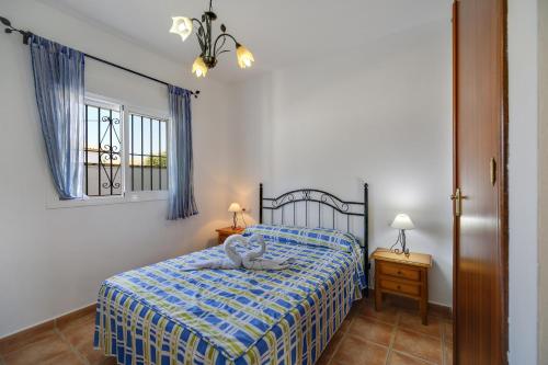 Un dormitorio con una cama con una manta azul y blanca. en Los paraisos 1, en Conil de la Frontera