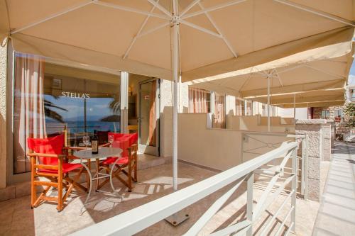 a patio with a table and chairs under an umbrella at Stella's Apartments in Tolo