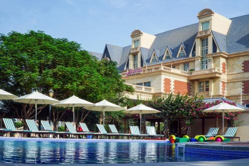 a hotel with chairs and umbrellas next to a swimming pool at Al Aziziyah Boutique Hotel By The Torch in Doha