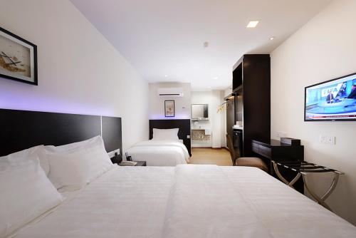 a hotel room with two beds and a flat screen tv at ERNES Hotel Bayu Mutiara in Bukit Mertajam