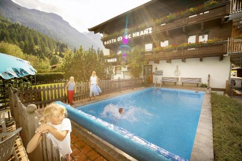 a young child standing next to a swimming pool at Aparthotel Garni Schranz in Wald im Pinzgau