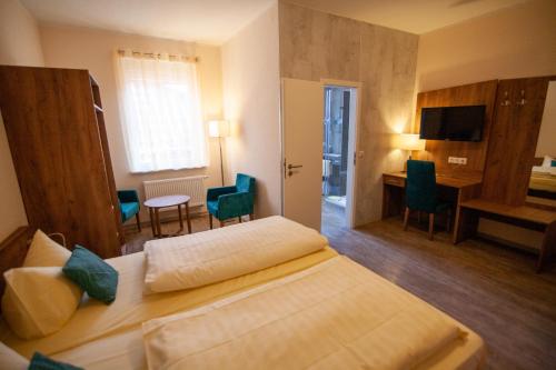 BimbachにあるTraditionsgasthof Zum Luedertalのベッド、デスク、椅子が備わるホテルルームです。