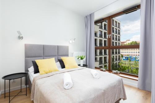 um quarto com uma cama e uma grande janela em Apartments Browary Warszawskie by Renters em Varsóvia