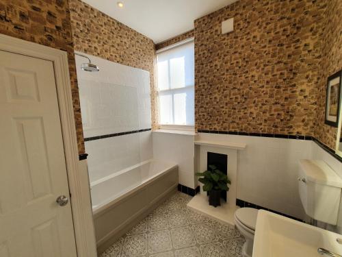 a bathroom with a bath tub and a toilet at Apartment 6 Rowntree House in York