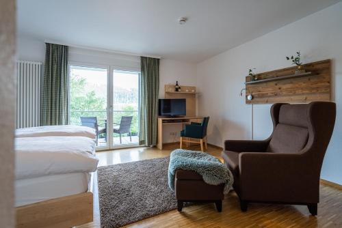 ein Schlafzimmer mit einem Bett, einem Stuhl und einem Schreibtisch in der Unterkunft NATURE TITISEE - Easy.Life.Hotel. in Titisee-Neustadt