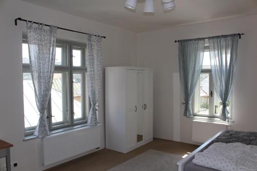1 dormitorio con paredes blancas y ventanas con cama en Vila Dorothea en Banská Štiavnica