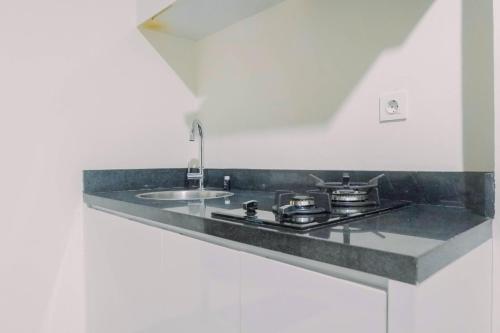 a kitchen counter with a stove and a sink at Lavish 2BR Apartment at Grand Sungkono Lagoon By Travelio in Surabaya
