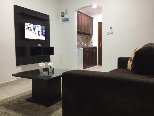 a living room with a couch and a flat screen tv at Tunaib Plaza in Aţ Ţunayb