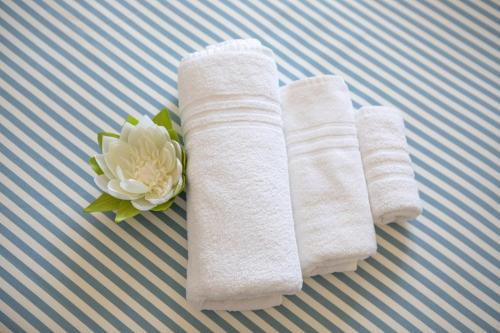 zwei weiße Handtücher und eine Blume auf einem Bett in der Unterkunft Hotel San Francisco in Lido di Savio