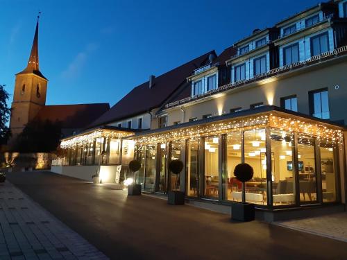 un bâtiment avec des lumières de Noël en face d'une église dans l'établissement Rossano Boutique Hotel & Ristorante, à Ansbach