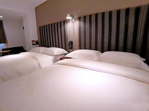 a row of white beds in a hotel room at River inn Station in Kaohsiung