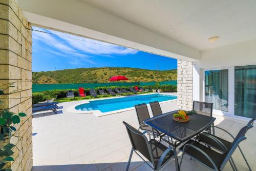 a patio with a table and chairs and a swimming pool at Villa Olivia Trogir in Trogir