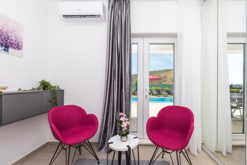 two pink chairs in a living room with a tv at Villa Olivia Trogir in Trogir