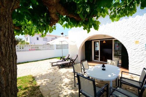 Un patio con una mesa y sillas debajo de un árbol. en Casas Montgrí, en Empuriabrava