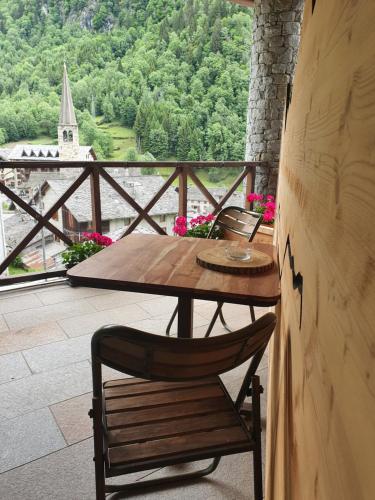 a wooden table and chair on a balcony with a view at MH Olen Boutique Hotel in Alagna Valsesia