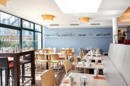 ein Restaurant mit Tischen, Stühlen und Fenstern in der Unterkunft Holiday Inn Dresden - City South, an IHG Hotel in Dresden