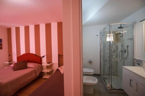 um quarto cor-de-rosa com uma cama e um chuveiro em B&B Porta di Ponte em Agrigento