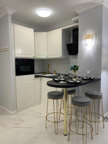 a kitchen with white cabinets and a table with stools at Hamptons Apartment in Świnoujście
