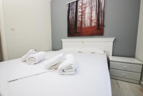 a bedroom with a white bed with towels on it at Ifigenia's Apartments in Stoupa