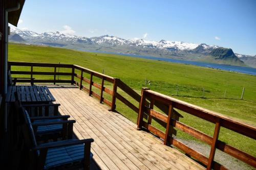 a deck with chairs and a fence with snow covered mountains at Sudur-Bár Guesthouse in Grundarfjordur