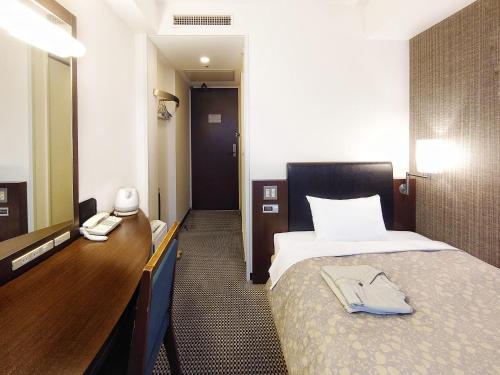 Habitación de hotel con cama, tocador y espejo. en Takaoka Manten Hotel Ekimae, en Takaoka