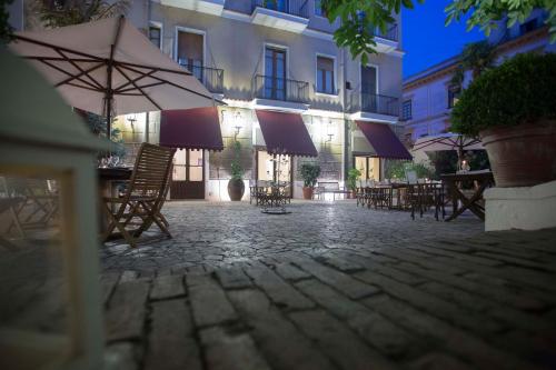 an outdoor patio with tables and chairs and an umbrella at Hotel Victoria Maiorino in Cava deʼ Tirreni