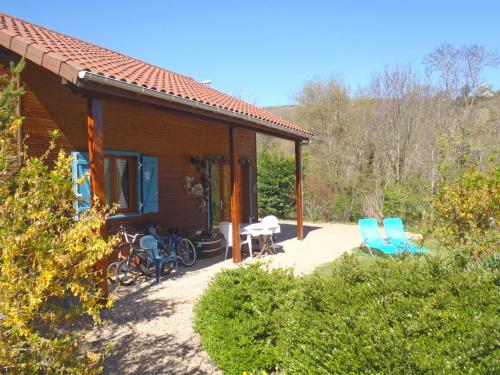 une maison avec 2 chaises bleues et une terrasse dans l'établissement LES CHALETS DE LA VIGNE GRANDE, à Saint-Floret