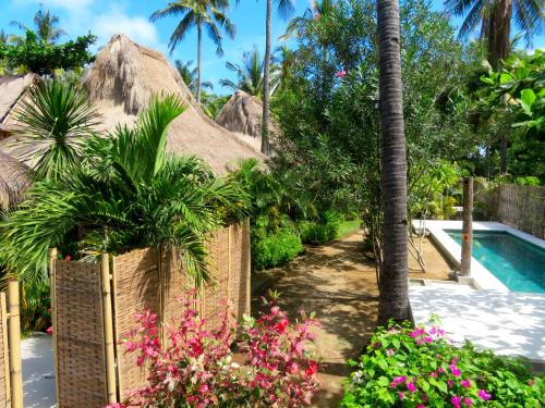 ein Resort mit einem Pool und Blumen in der Unterkunft Breathe Villa Meno in Gili Meno