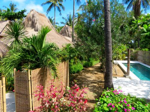 a resort with a swimming pool and flowers at Breathe Villa Meno in Gili Meno