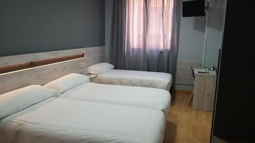 two beds in a room with white sheets at Hotel Alda Centro Oviedo in Oviedo