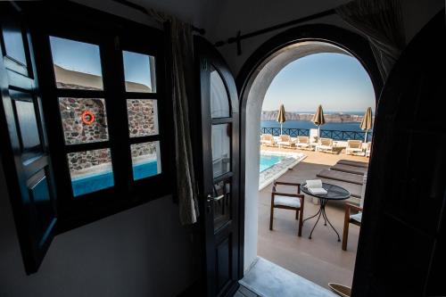 an open door to a balcony with a view of a pool at Afroessa Hotel by Pearl Hotel Collection in Imerovigli