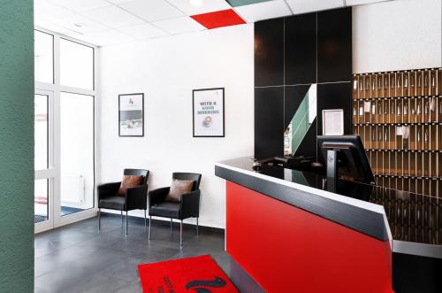 a waiting room with two chairs and a red counter at Good Morning Berlin City West in Berlin