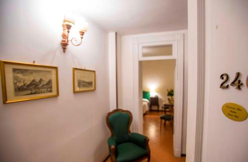 a living room with a green chair and a bedroom at Hotel Victoria Maiorino in Cava deʼ Tirreni