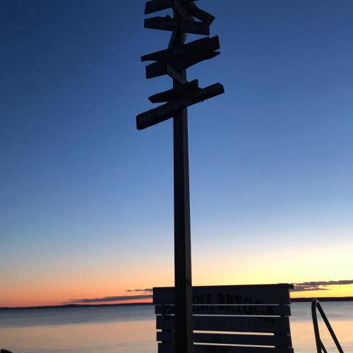 a street sign with a bench in front of the ocean at Pinglans bakficka in Gränna