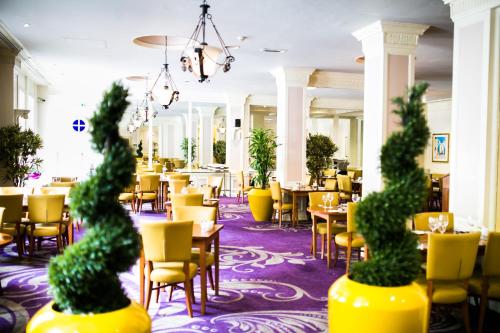 a restaurant with yellow chairs and tables and chairs at The Angel Hotel- Part of the Cairn Collection in Cardiff
