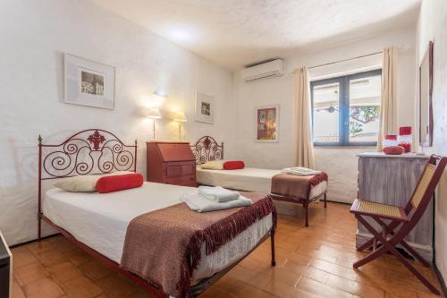 een slaapkamer met 2 bedden, een stoel en een raam bij Villa Morena in Albufeira