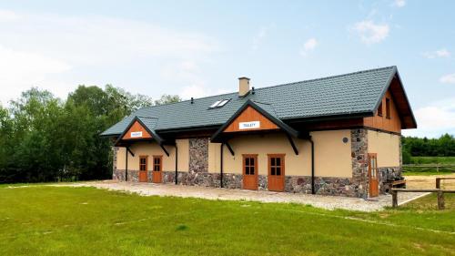a house with a black roof on a grass field at Camping Bartbo in Olsztyn