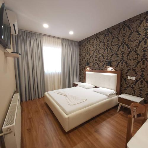 a bedroom with a large white bed and a window at Hotel Kocibelli POOL & SPA in Korçë