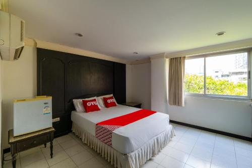 a bedroom with a bed with red pillows and a window at OYO 1042 Boon’s Residence (Sathorn) in Bangkok