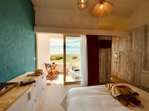 a bedroom with a bed and a view of a patio at Hôtel Île de Lumière in La Cotinière