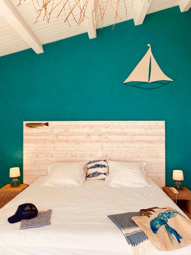 a bedroom with a large white bed with a green wall at Hôtel Île de Lumière in La Cotinière
