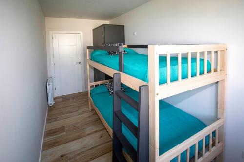 two bunk beds in a small room with blue sheets at Apartamentos Salitre in Soto de la Marina