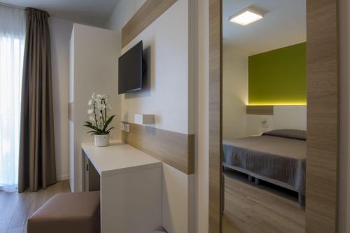 a room with a bed and a desk with a television at Almalux Jesolo Wellness & Spa 3 stelle superior in Lido di Jesolo