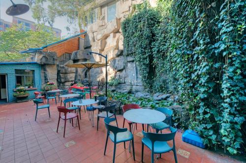 a patio with tables and chairs and a stone wall at Kunming Upland International Youth Hostel ,near the city center ,2 mins walk to the subway, 2 mins walk to the Green Lake, Close to Yuan tong Temple, Old street, Yunnan University, convenient payment and visa cards are accepted in Kunming