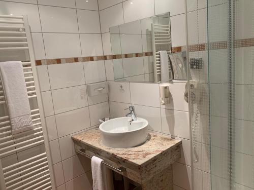 uma casa de banho branca com um lavatório e um espelho em The KRAL - Business Hotel & Serviced Apartments em Erlangen